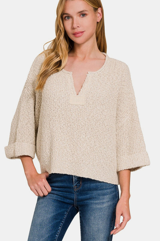 Woman wearing notched side slit patch sweater with short sleeves and rolled cuffs, showcasing a modern and effortless style.