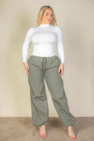 Plus size model wearing green drawstring waist parachute pants with a white top, showcasing comfort and style.