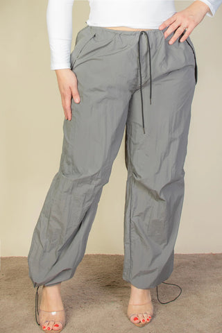 Plus size parachute pants with drawstring waist and elastic band, crafted from durable nylon, featuring front pockets and toggle detail.