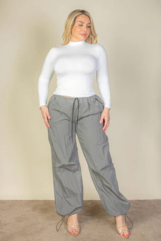 Plus size drawstring waist parachute pants in gray, featuring an elastic waistband and front pockets, paired with a white top.