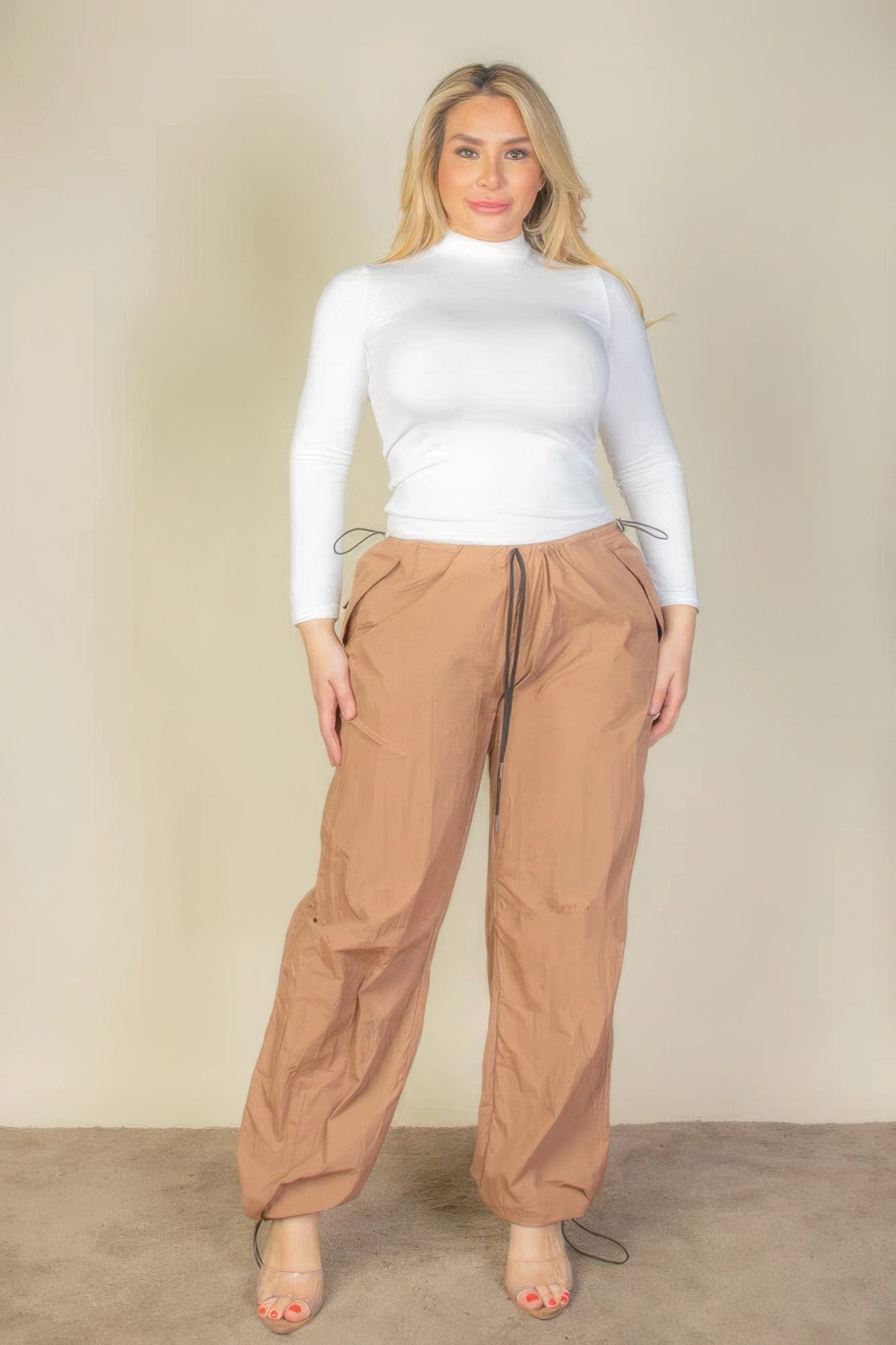 Plus size model wearing brown drawstring waist parachute pants and white top, showcasing comfort and style.