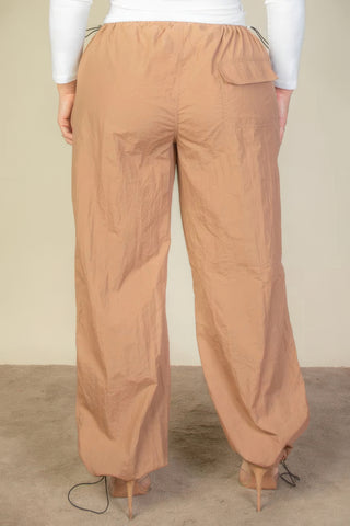 Plus size drawstring waist parachute pants in tan color, back view showcasing elastic band and toggle details.