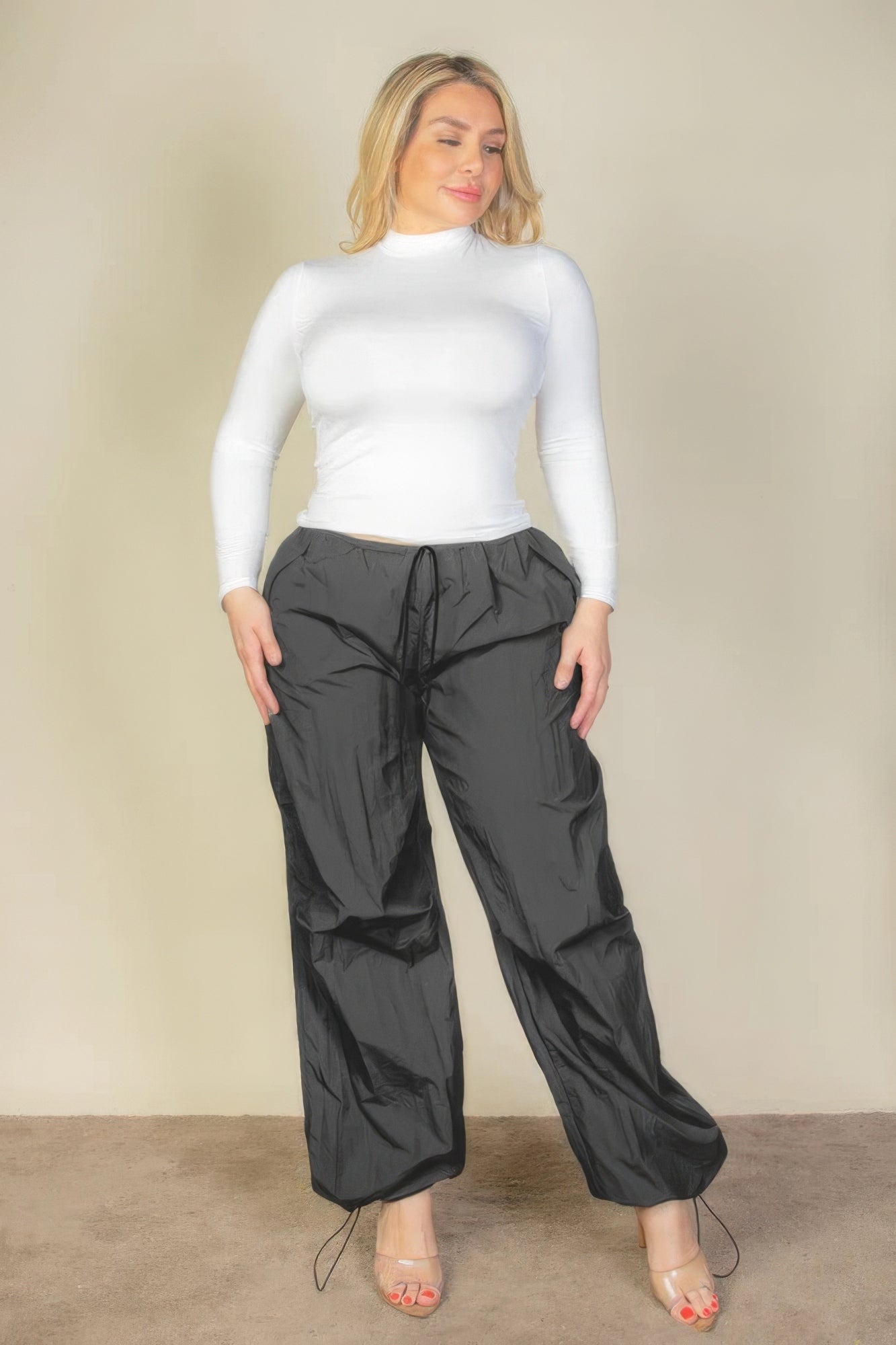 Plus Size Drawstring Waist Parachute Pants in black with a stylish fit, shown on a model wearing a white top and heels.