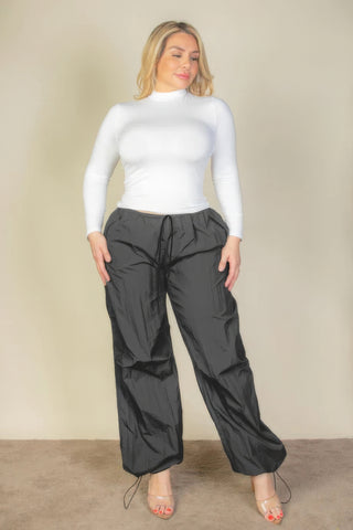 Plus Size Drawstring Waist Parachute Pants in black with a stylish fit, shown on a model wearing a white top and heels.