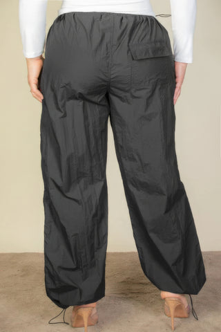Plus size drawstring waist parachute pants in black nylon, back view showing elastic band and toggle tighten features.