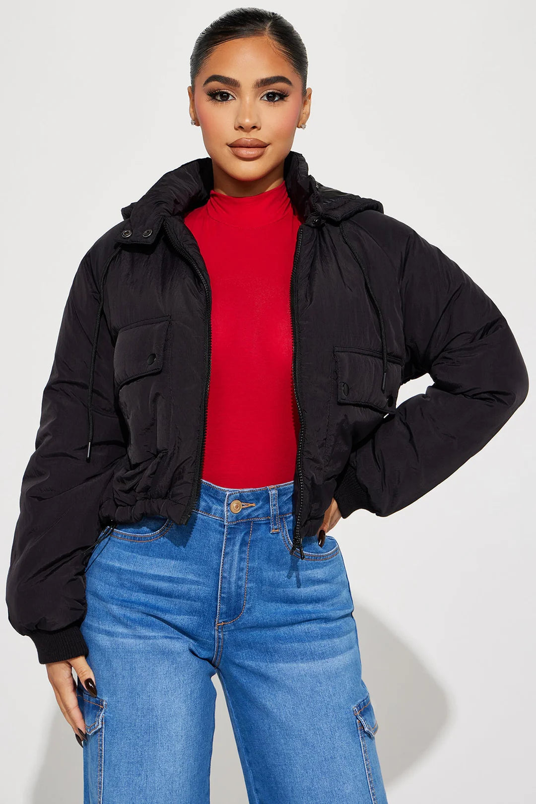 Woman wearing a black nylon puff hood jacket with a red top and blue jeans, showcasing a stylish and streamlined look.