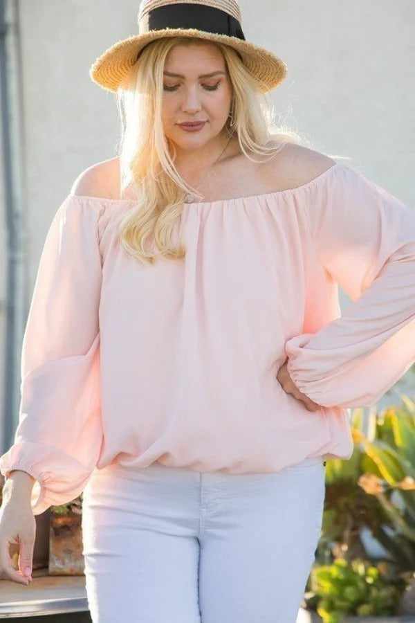 Woman wearing off shoulder long bubble sleeve solid top in rose, paired with a straw hat, white pants, plus size fashion.