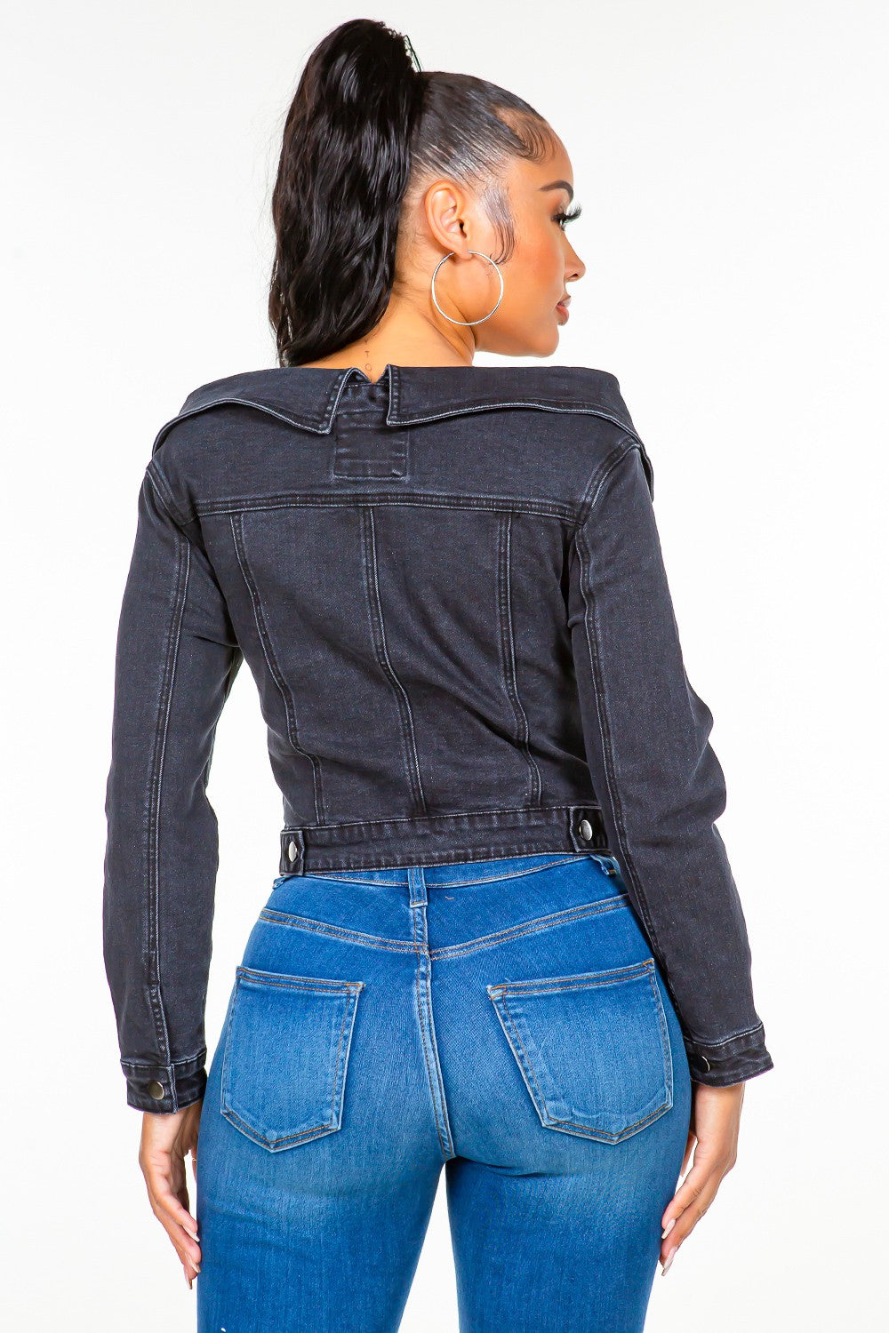 Woman wearing off-shoulder lace-up denim jacket, showcasing back view with fitted style.