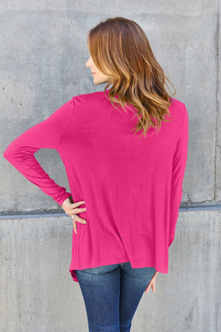 Woman wearing open front long sleeve pink cardigan, showing back view with slightly stretchy rayon-spandex blend, paired with jeans.