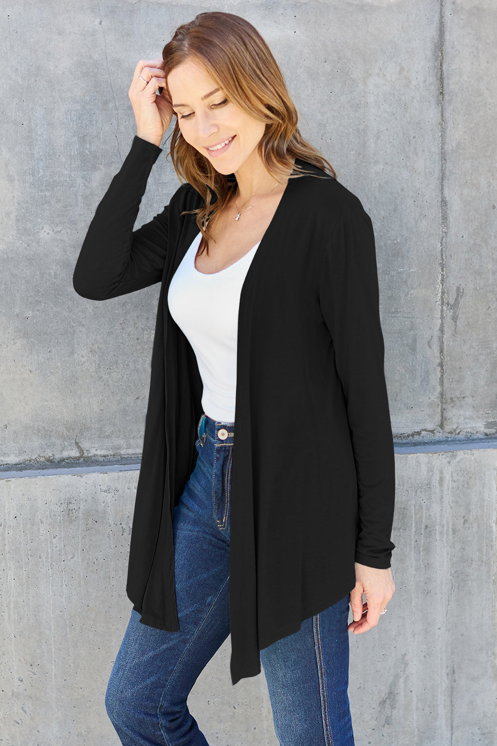 Woman wearing black open front long sleeve cardigan over white top and jeans, showcasing chic, versatile fashion style.