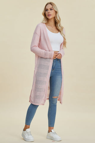 Woman wearing a pink open front longline cardigan with openwork design and moderate stretch, paired with jeans and a white top