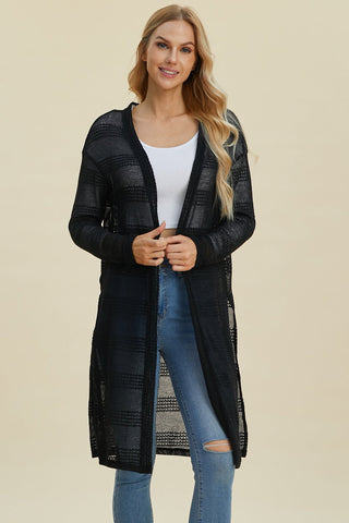 Woman wearing open front longline cardigan with openwork design and moderate stretch in black, made of 100% polyester.
