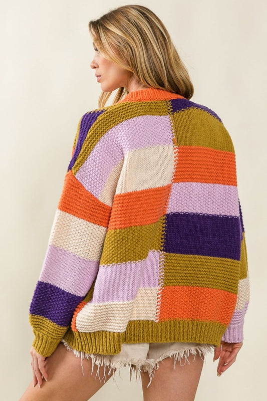 Woman wearing an orange checkered color block sweater cardigan with vibrant patterns and an open front design for stylish layering.