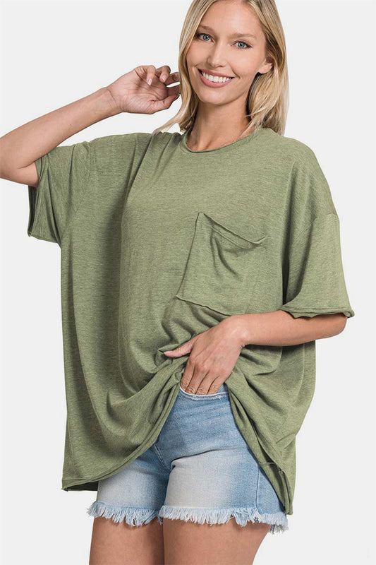 Woman wearing drop shoulder oversized front pocket t-shirt in olive green, paired with denim shorts, showcasing casual style.