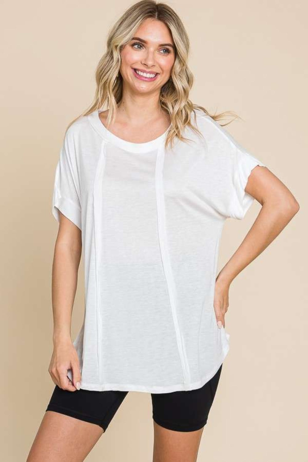 Woman wearing a white round neck short sleeve t-shirt with a relaxed fit, paired with black shorts, showcasing casual style.