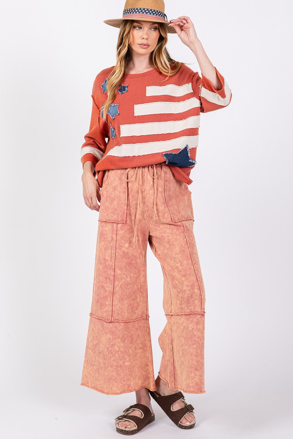 Woman wearing pink mineral washed terry wide leg pants with a striped top and hat, showcasing casual chic style.