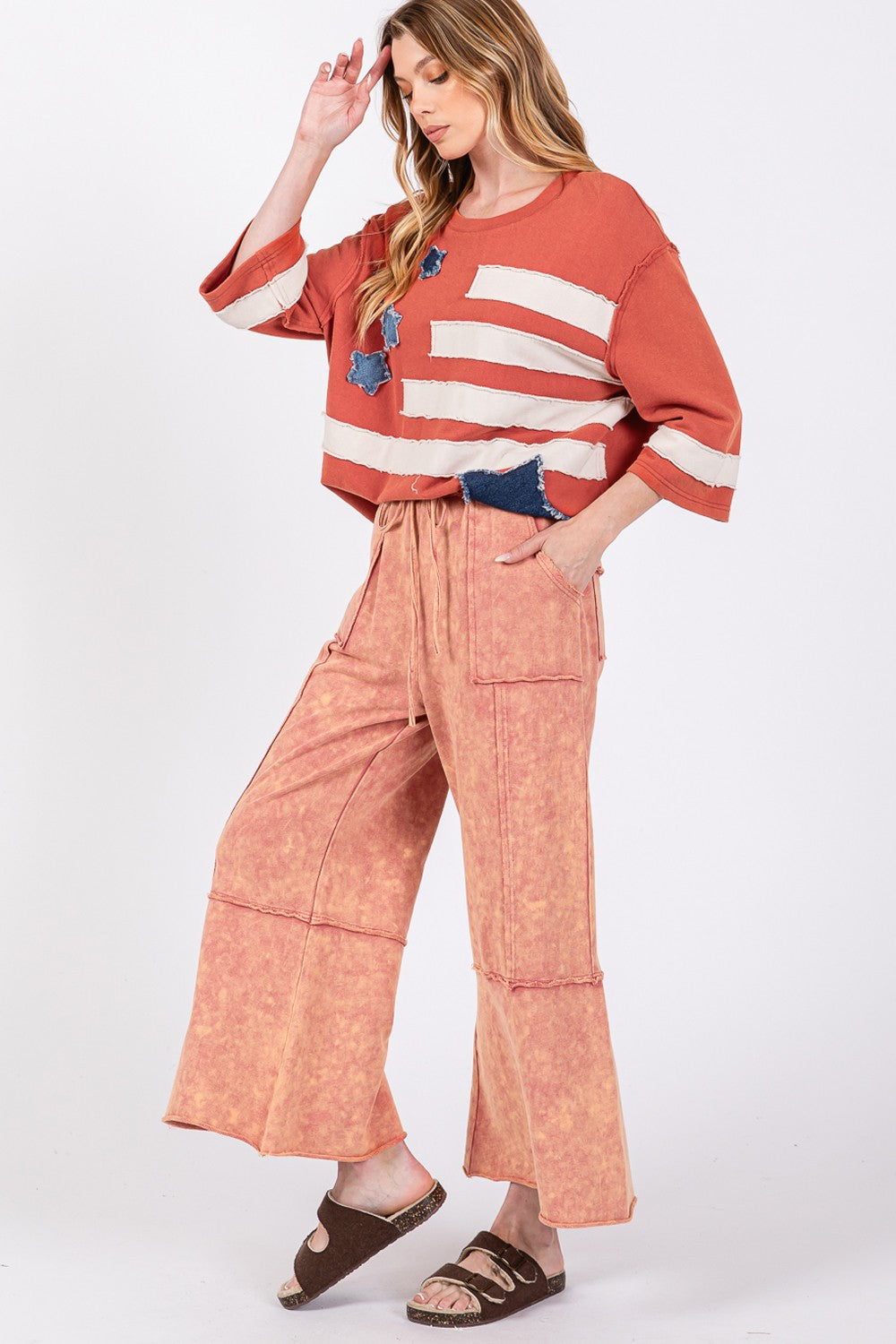 Woman wearing pink mineral washed terry wide leg pants and orange striped top, showcasing relaxed style and comfort.