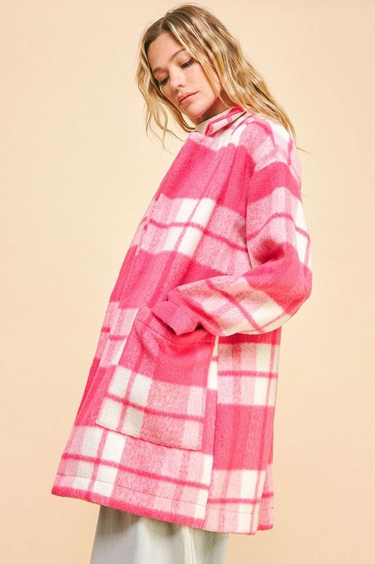 Woman wearing a pink plaid open front longline coat with drop shoulders and pockets, made from 100% polyester.