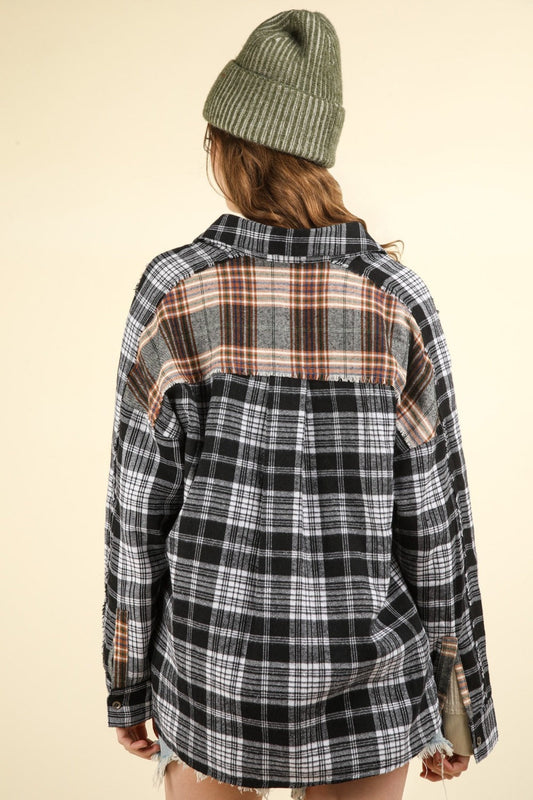 Person wearing oversized black contrast plaid shirt with raw detail, showing back view and green beanie, casual style.