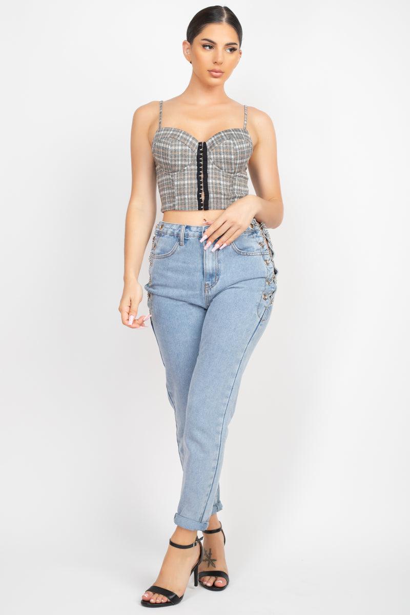 Woman wearing a plaid sweetheart crop top with hook & eye front closure and high-waisted blue jeans.