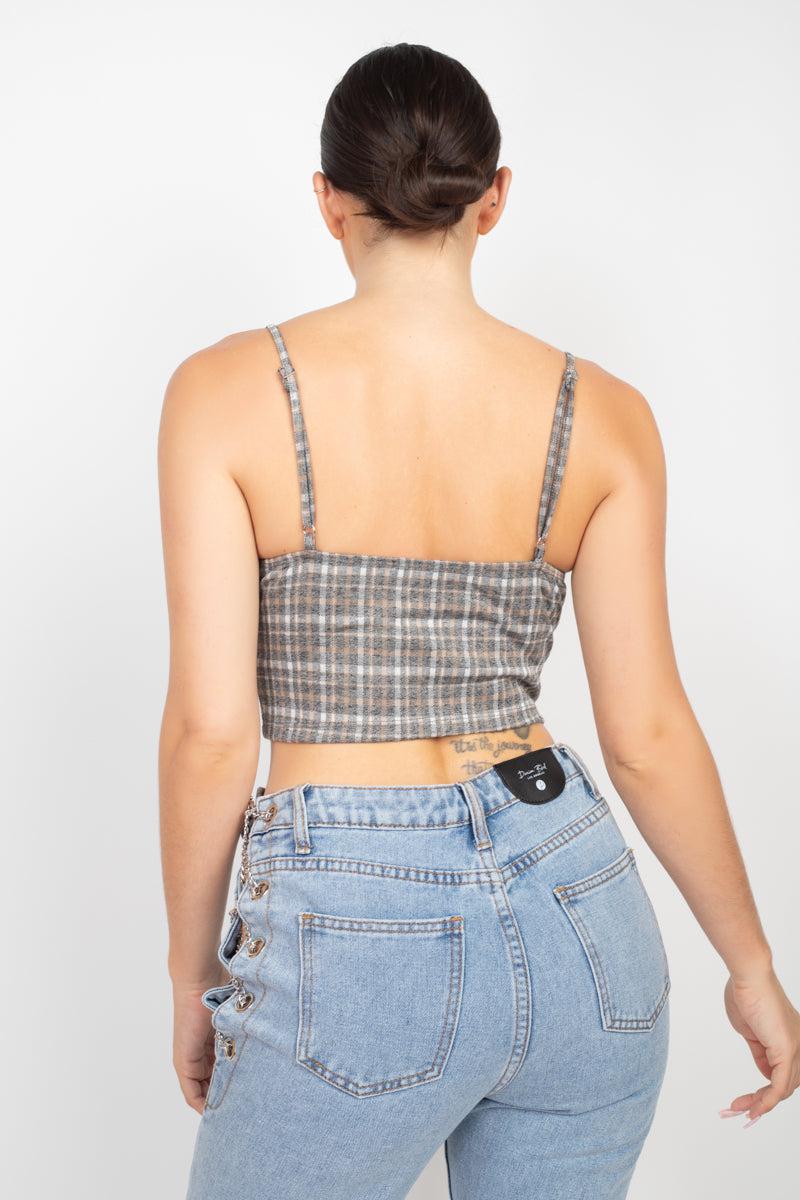 Woman wearing plaid sweetheart crop top with adjustable cami straps and blue jeans, viewed from the back.