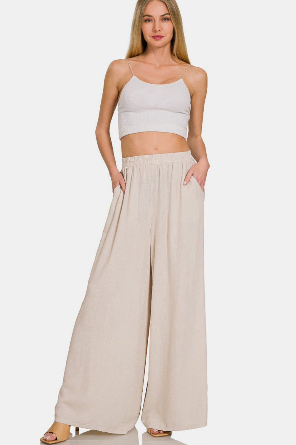 Woman wearing pleated linen blend wide leg pants with pockets, made of 25% linen and 75% rayon, showcasing casual chic style.