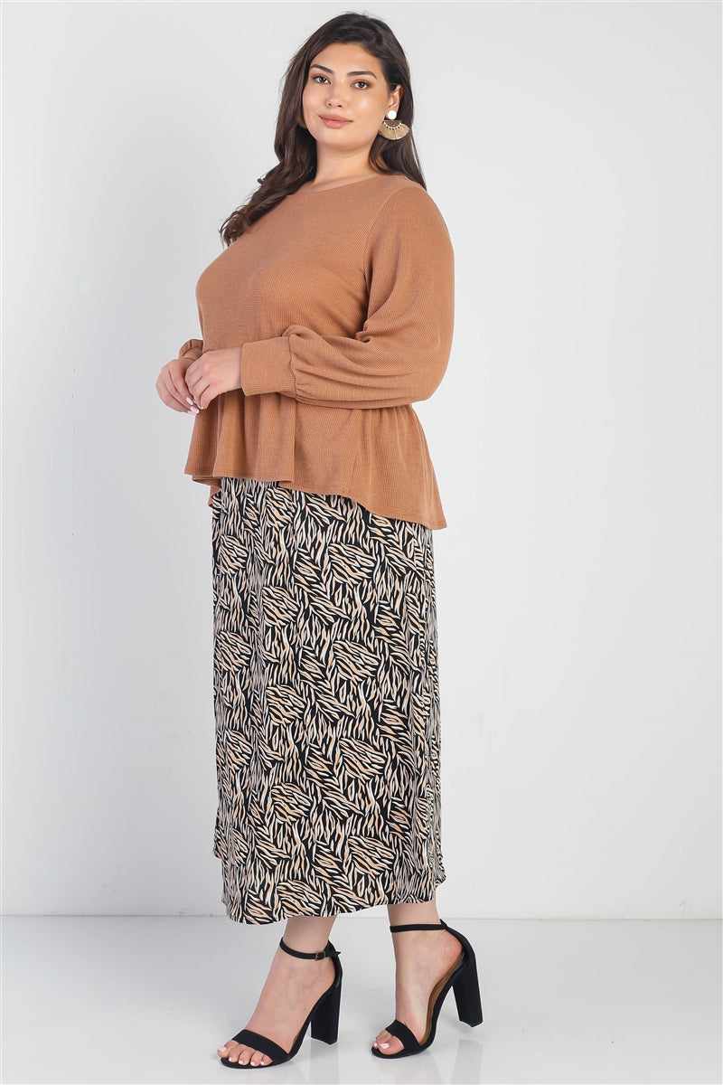 Plus size woman in caramel waffle long sleeve top with cuffed sleeves and flare hem, styled with patterned skirt and heels.