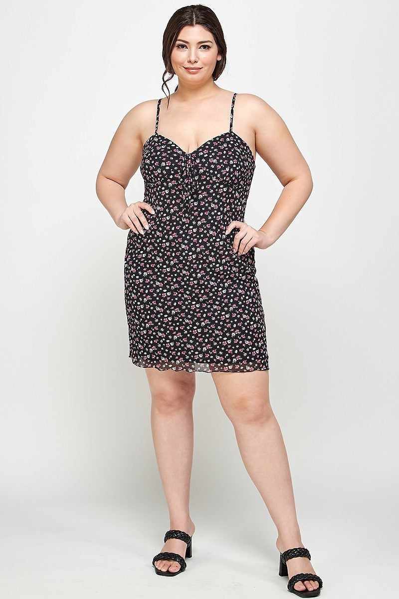 Plus-size woman in a black ditsy floral print cami dress with sweetheart neckline and ruffled hem, showcasing a relaxed fit.