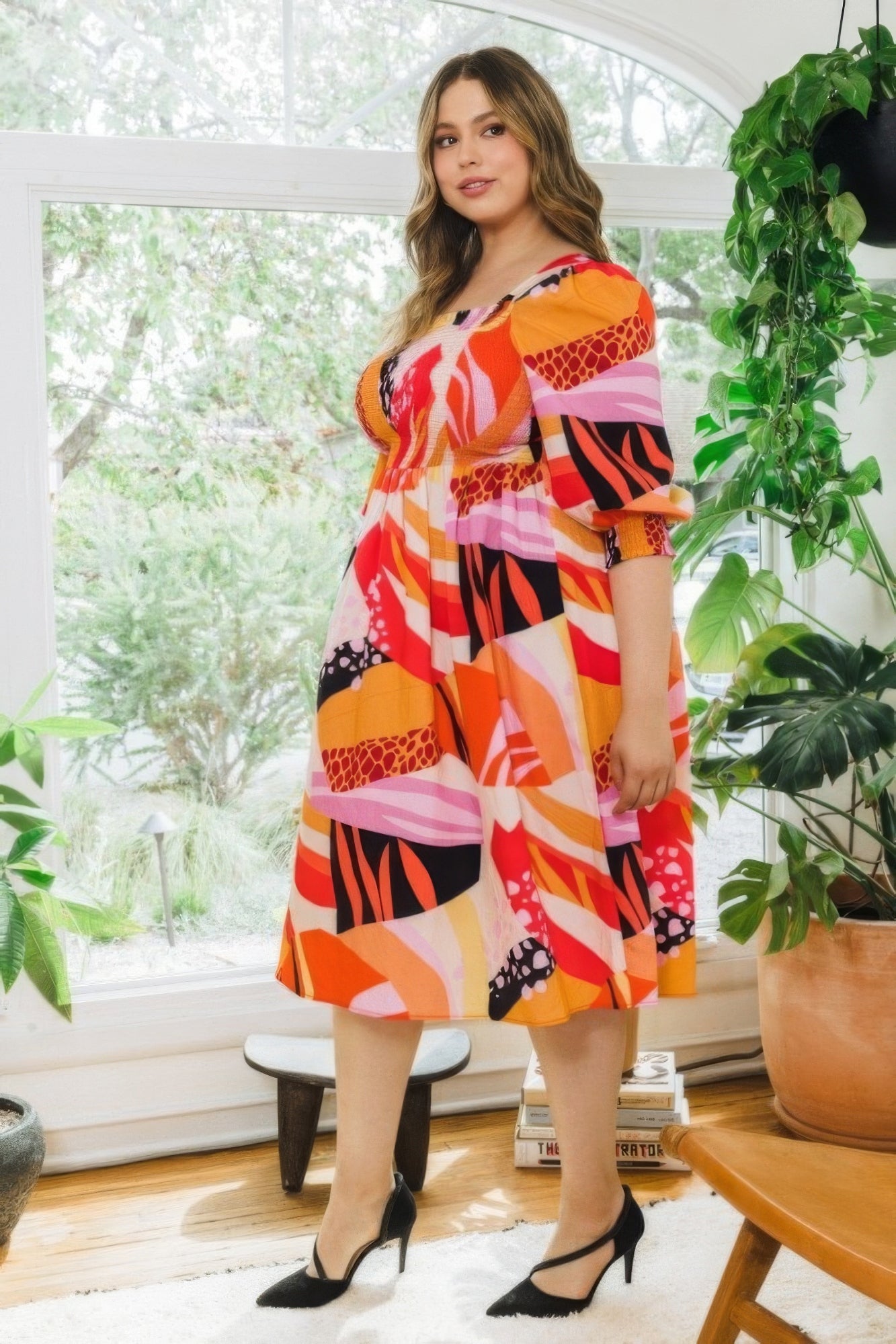 Plus-size model in coral floral print square neckline midi dress with 3/4 puff sleeves and smocked bodice, perfect for any occasion.