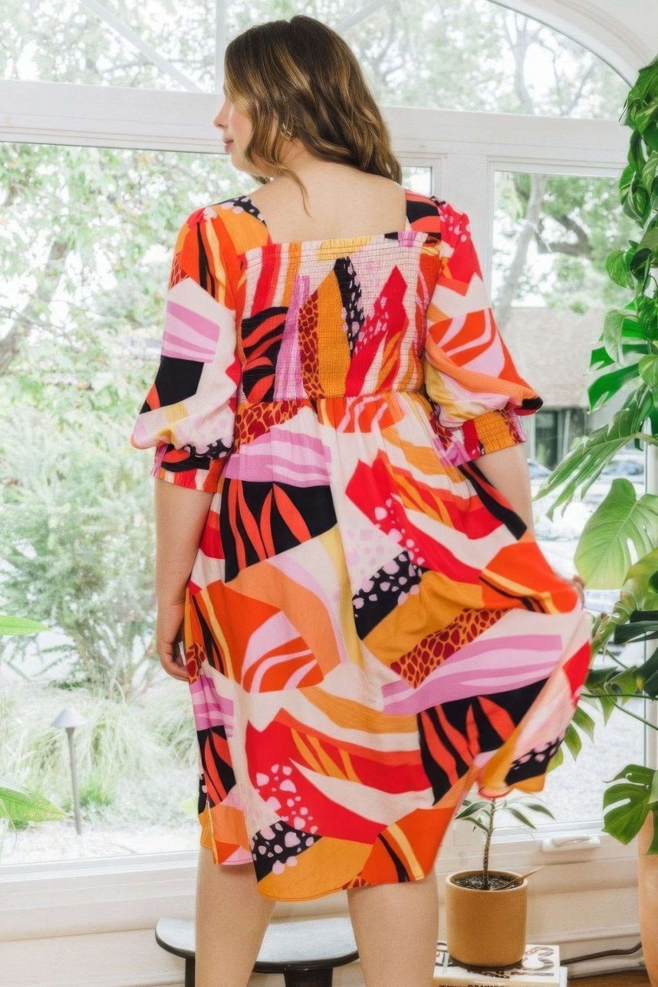 Plus floral print midi dress with square neckline and puff sleeves in coral multi-color, shown on model in a bright indoor setting.