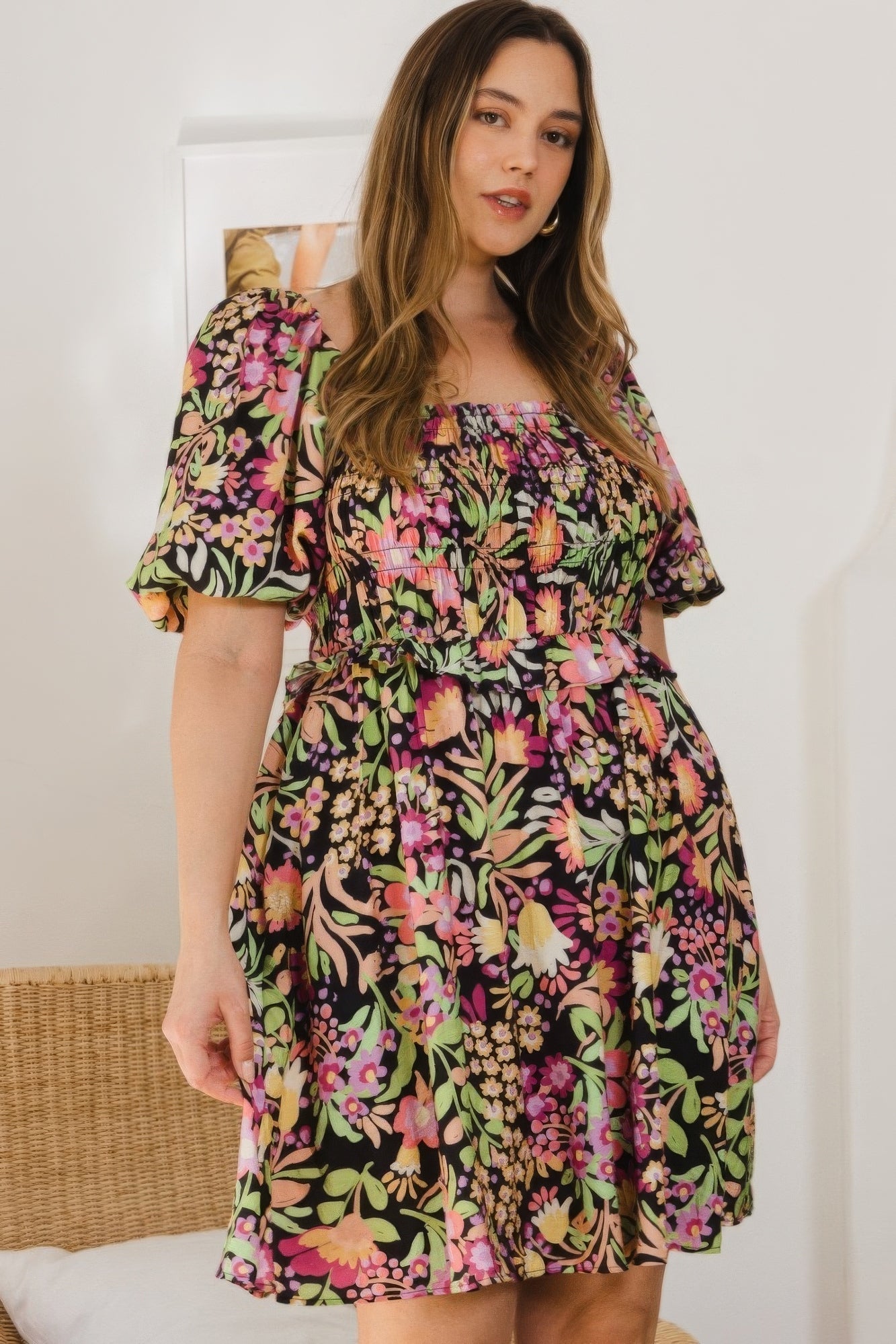 Plus-size floral mini dress with square neckline, puff sleeves, and tie-back detail in vibrant colors on black background.