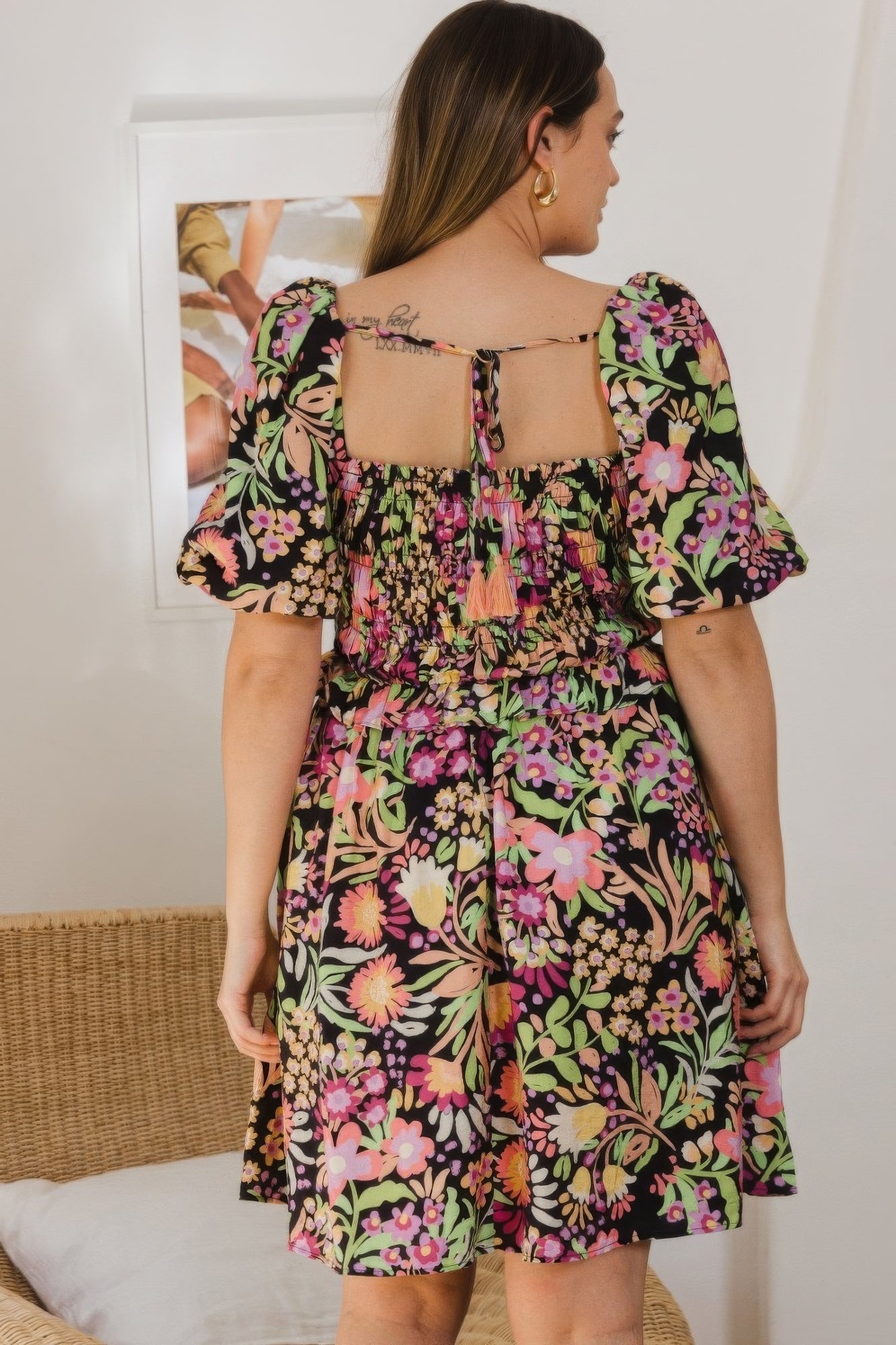 Plus size floral mini dress with center tie-back, puff sleeves, and smocked bodice on a chic black base with vibrant floral print.