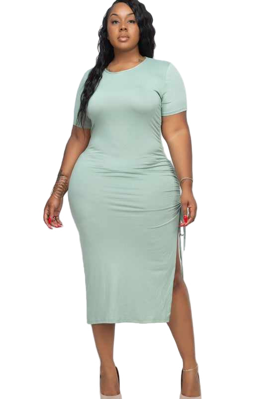 Plus size green midi dress with adjustable ruched side, short sleeves, and side slit, worn by model in 1XL size.