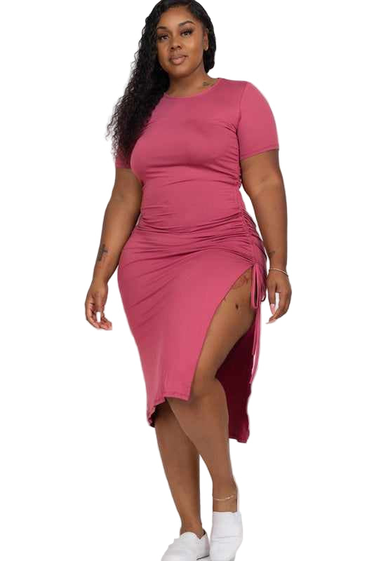 Plus size model wearing a pink casual midi dress with ruched side and side slit, crafted from stretch knit fabric, short sleeves, 1XL.