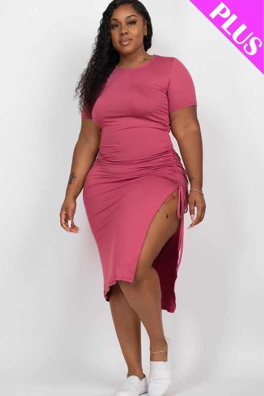 Plus size model wearing a pink casual midi dress with ruched side and side slit, crafted from stretch knit fabric, short sleeves, 1XL.