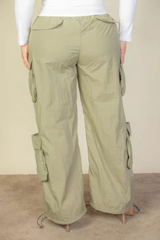 Plus size nylon parachute pants with flap pockets and drawstring, shown in light green, highlighting rear view and ruched detailing.