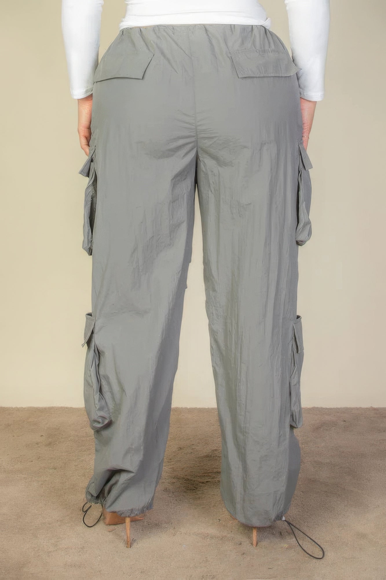 Plus size parachute pants with flap pockets and drawstring, made from lightweight gray nylon fabric, shown from the back.