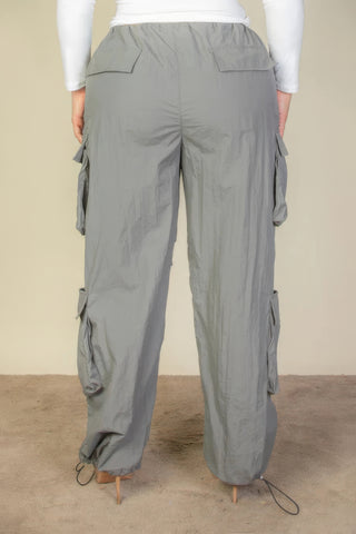 Plus size parachute pants with flap pockets and drawstring, made from lightweight gray nylon fabric, shown from the back.