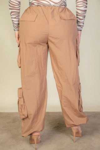 Plus size beige parachute pants with flap pockets and drawstring, shown from the back, highlighting ruched details and fit.