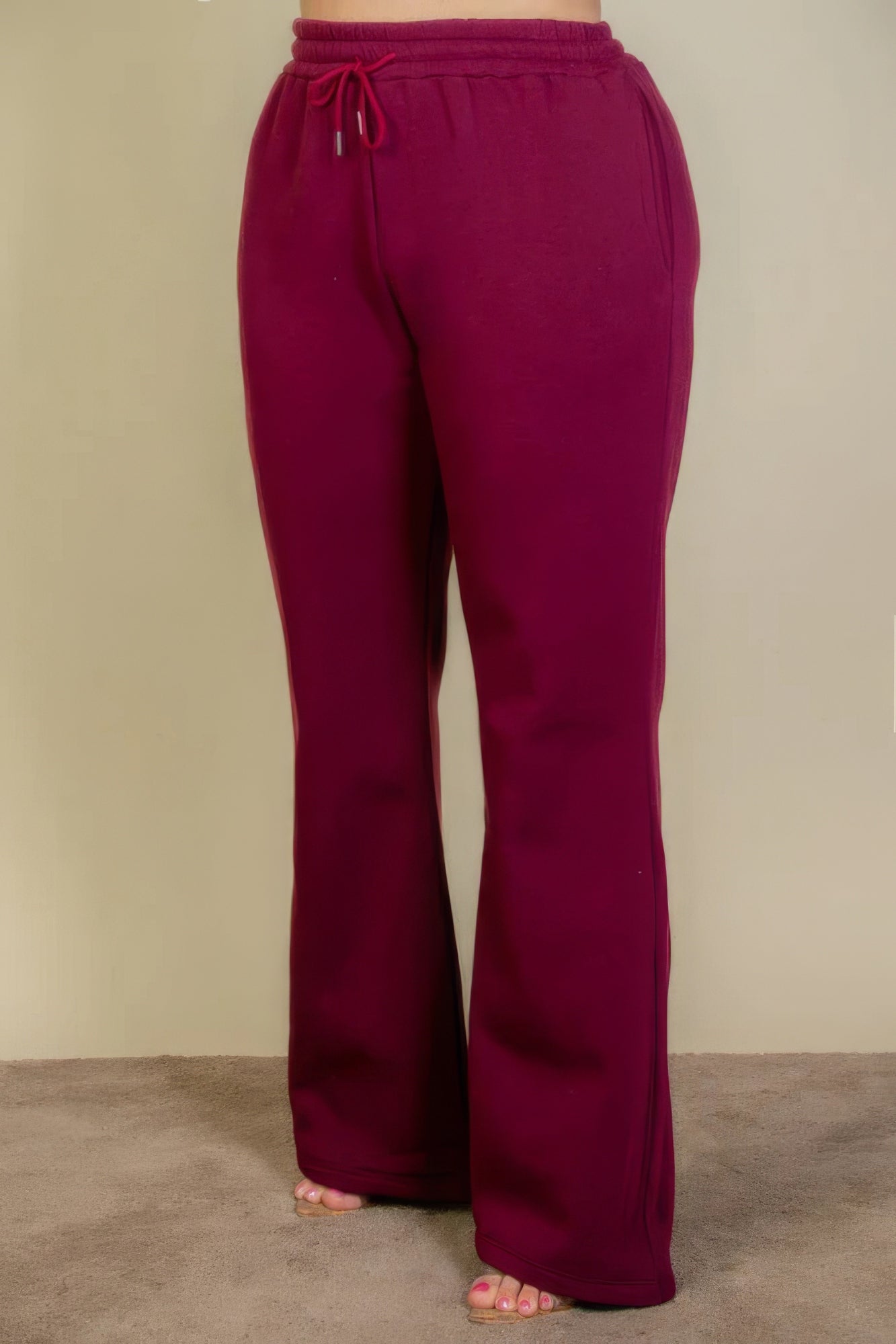 Plus size burgundy sweatpants with drawstring waist and slant pockets, featuring a bootcut silhouette for stylish comfort.