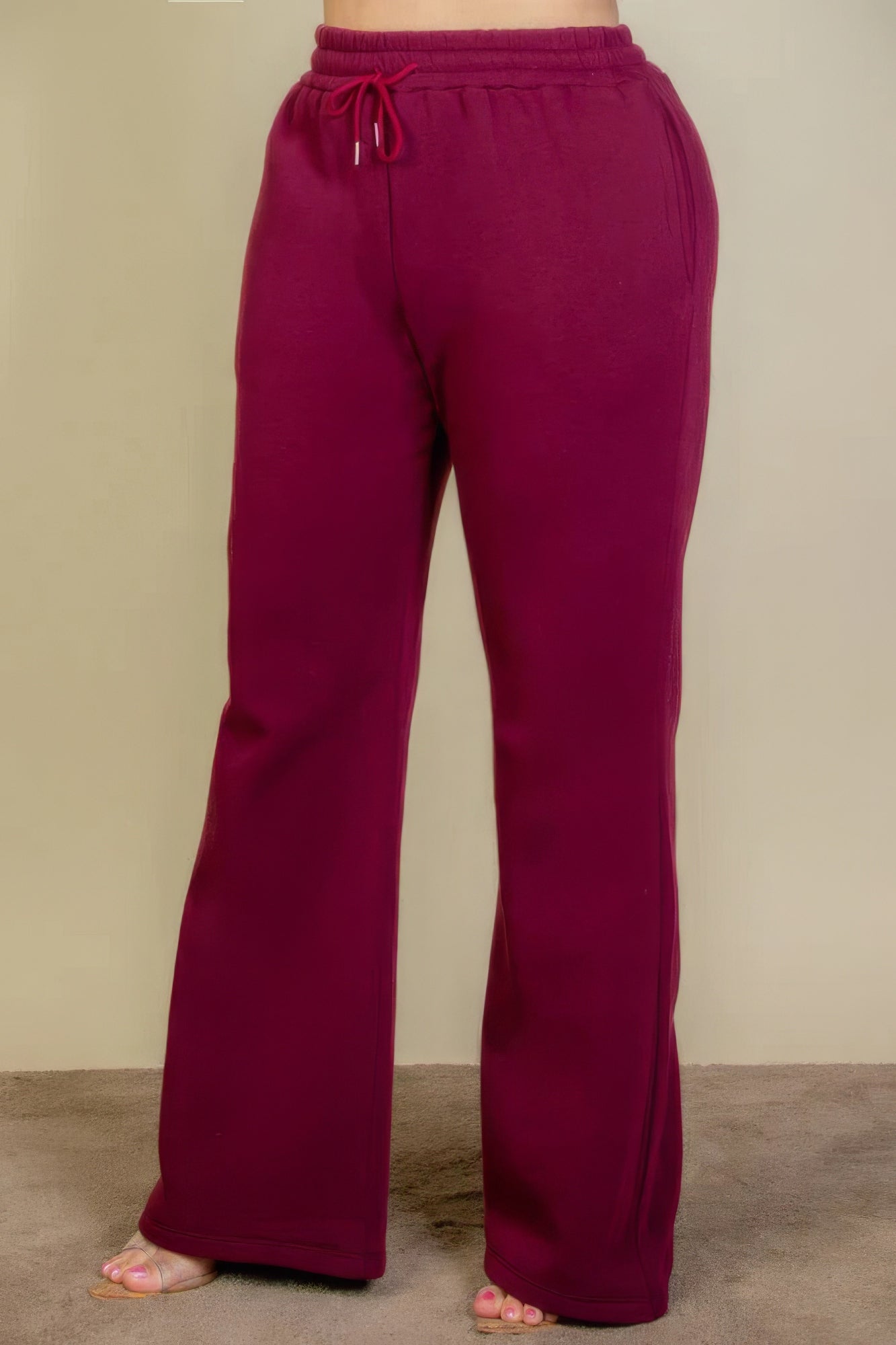 Plus size burgundy sweatpants with drawstring waist and slant pockets, featuring a flattering bootcut silhouette.