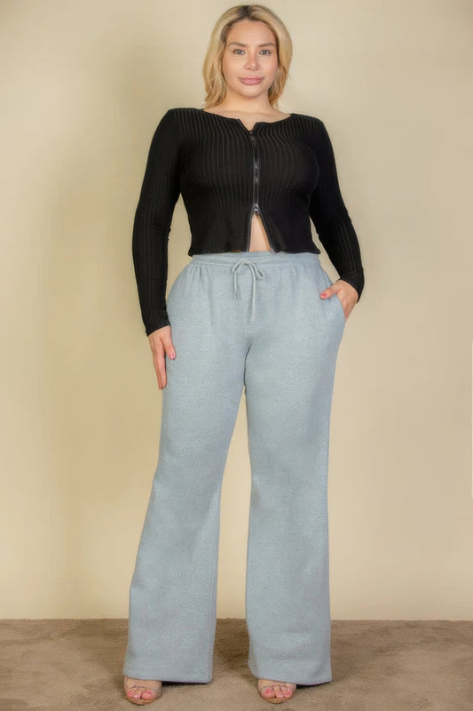 Plus size sweatpants with drawstring waist and slant pockets in olive, styled with a black top for a trendy casual look.