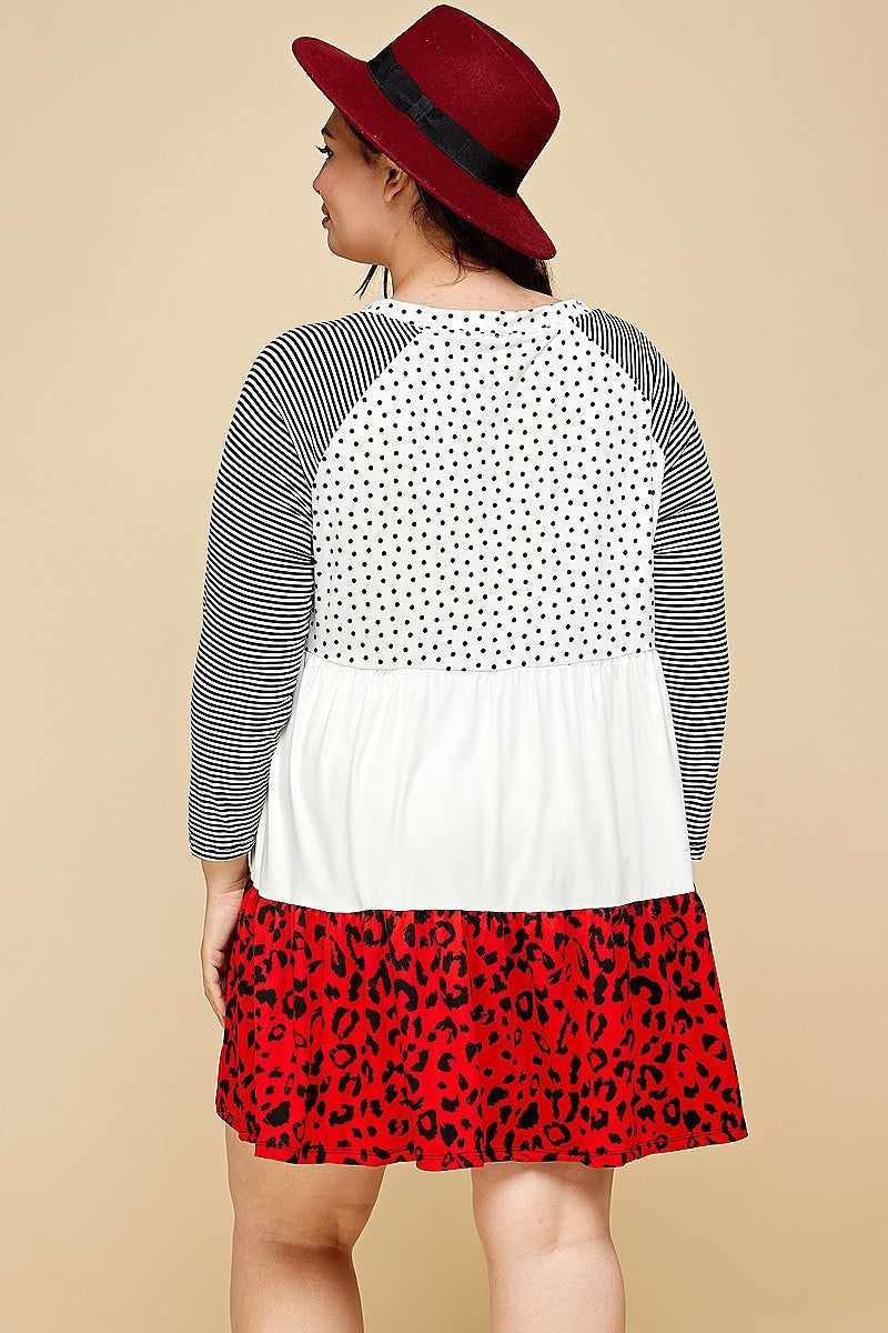 Plus size woman in a polka dot and animal print dress with striped sleeves, red tiered bottom, and a burgundy hat, rear view.