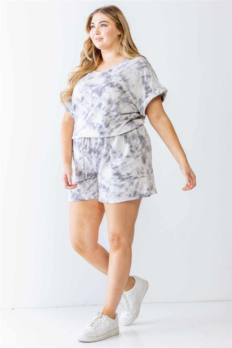 Plus size model wearing ivory and grey tie-dye romper with dolman sleeves, two pockets, and elasticized waistband.