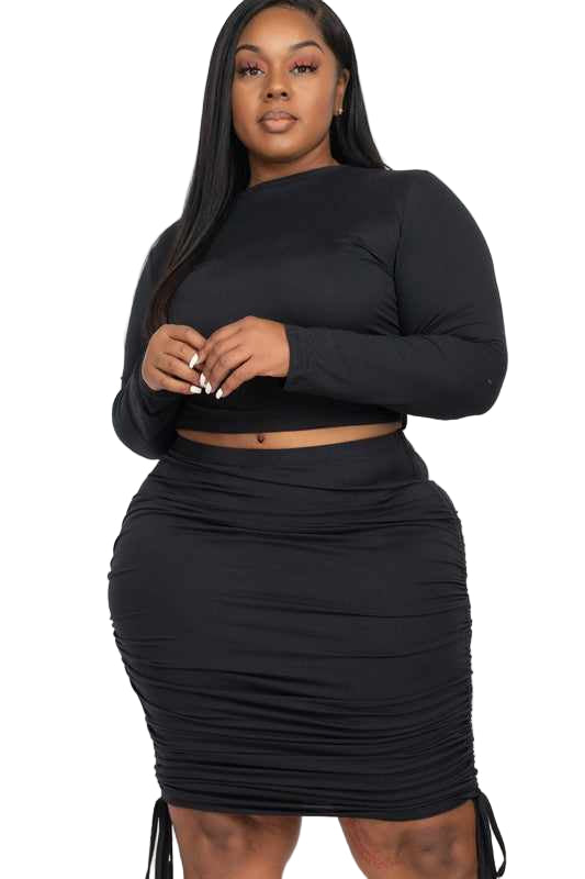 Plus size model wearing black ruched crop top and drawstring skirt set in high stretch jersey fabric, perfect for special occasions.