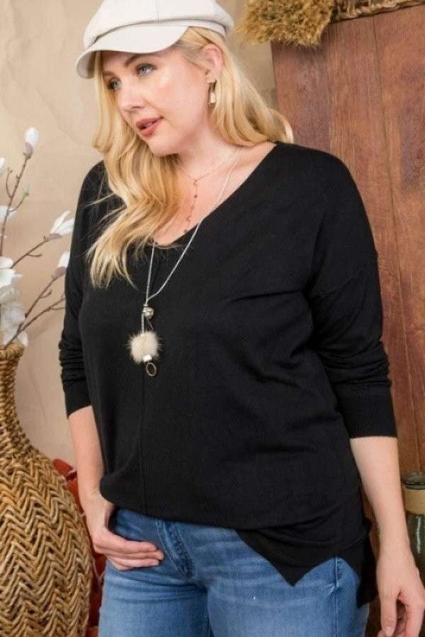 Plus size model wearing black V-neck hi-lo sweater with 3/4 sleeves and side slits, paired with jeans and a stylish cap.