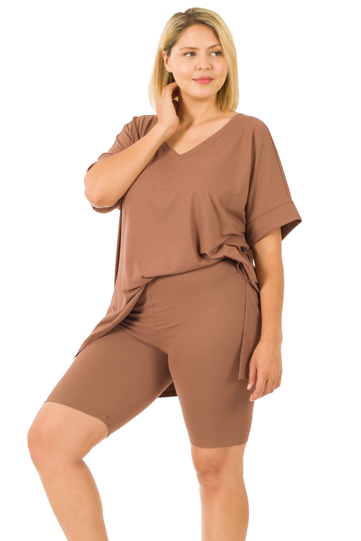 Woman wearing plus-size brown V-neck top and biker shorts, showcasing a relaxed fit with a buttery soft texture and high-low hem.