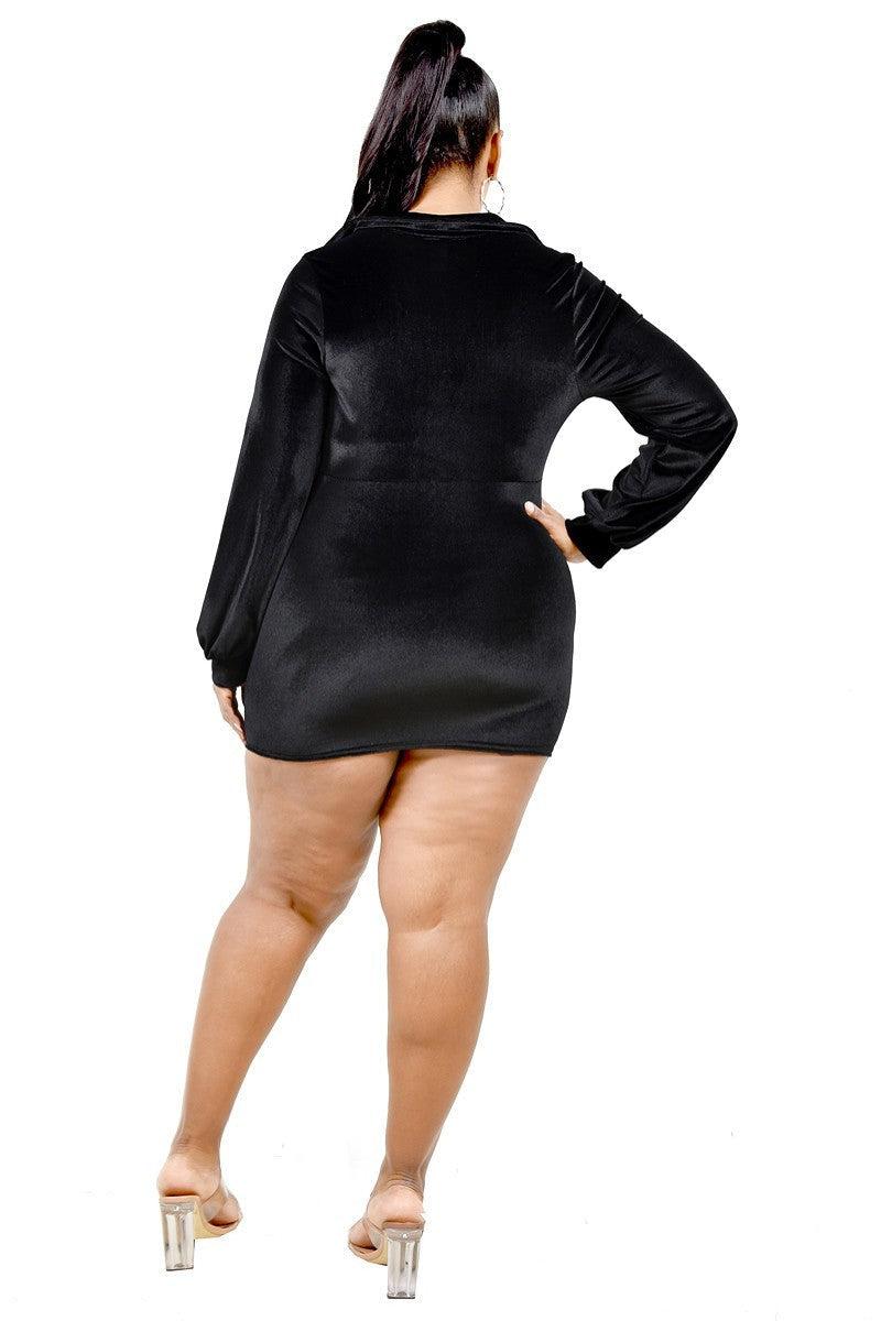 Plus size black velvet mini dress with bishop sleeves shown from the back, featuring a tie waist and stretch fabric.