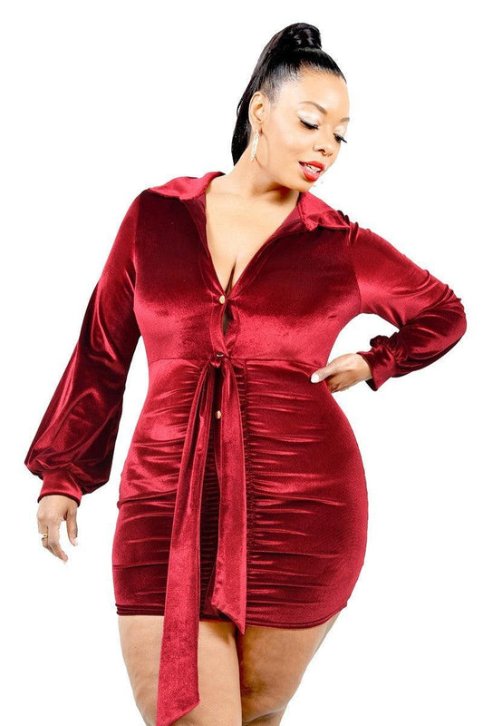 Plus size velvet mini dress in burgundy with bishop sleeves, tie waist, and V neckline with button closure.