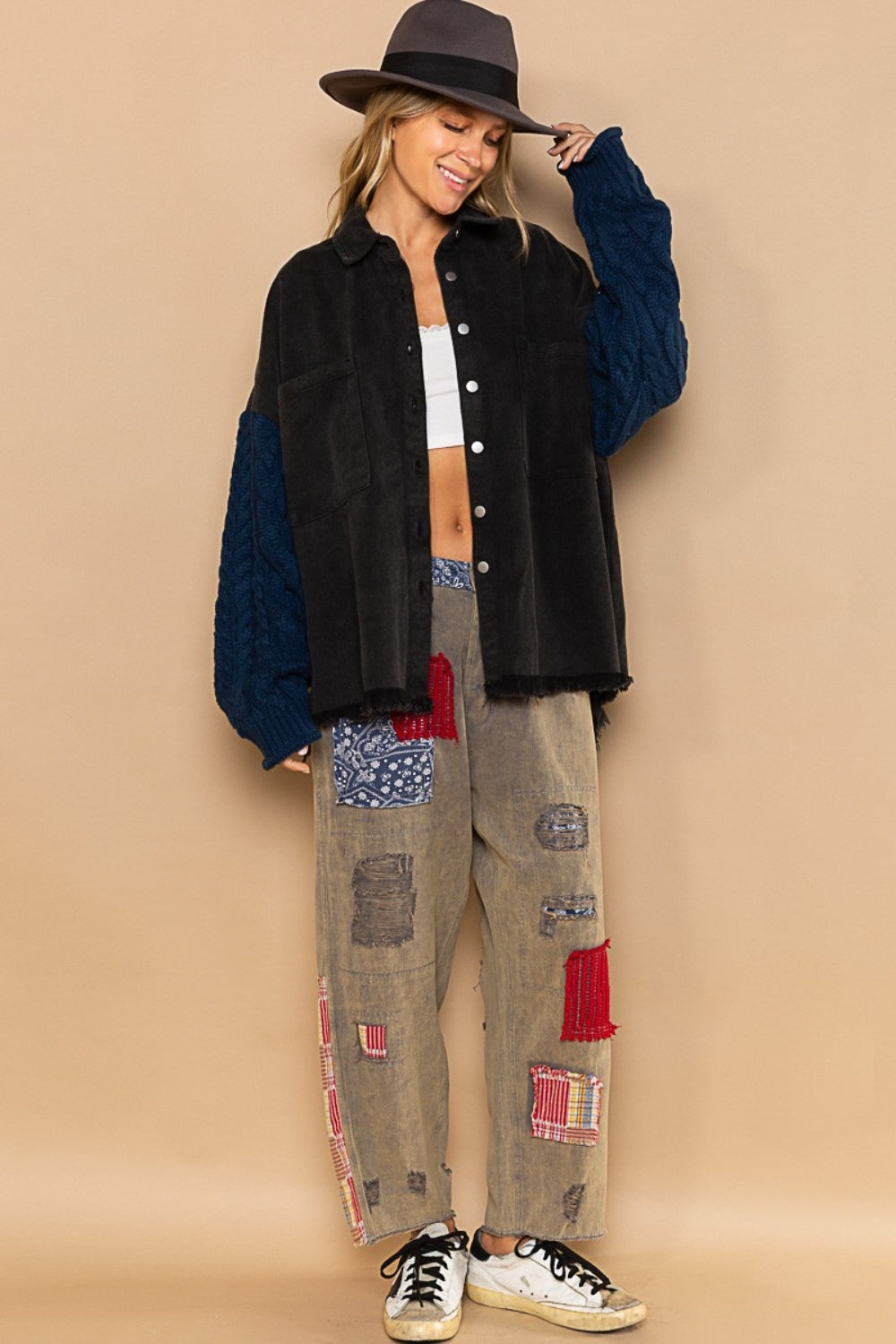 Woman wearing a POL Contrast Sweater Sleeve Button Down Shacket with cozy sweater sleeves and patchwork pants, styled with a hat.